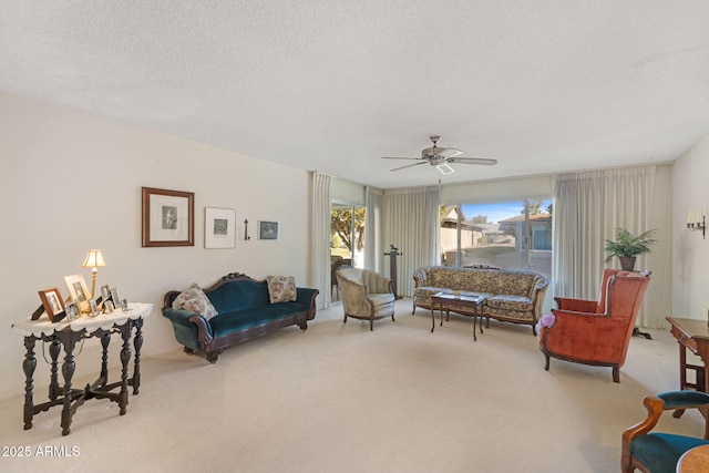 living room featuring ceiling fan, light colored carpet, and a textured ceiling