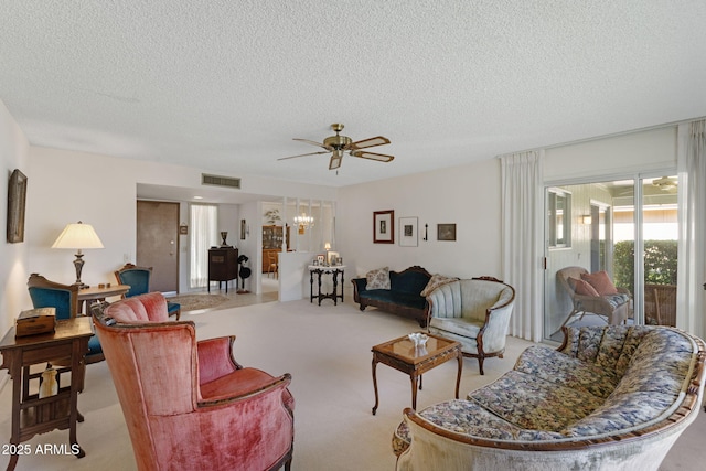 living room with ceiling fan with notable chandelier, light colored carpet, and a textured ceiling