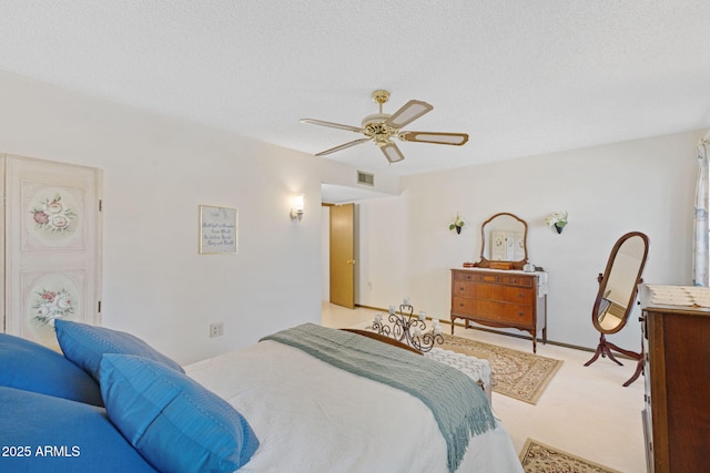 carpeted bedroom with ceiling fan and a textured ceiling