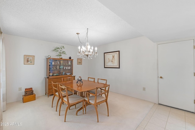 tiled dining room with an inviting chandelier and a textured ceiling