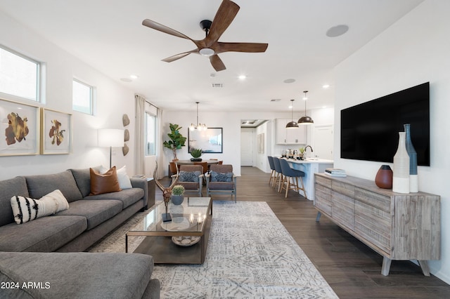 living room featuring ceiling fan with notable chandelier, dark hardwood / wood-style flooring, and sink