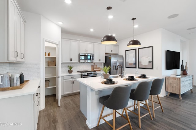 kitchen featuring white cabinetry, an island with sink, pendant lighting, and appliances with stainless steel finishes