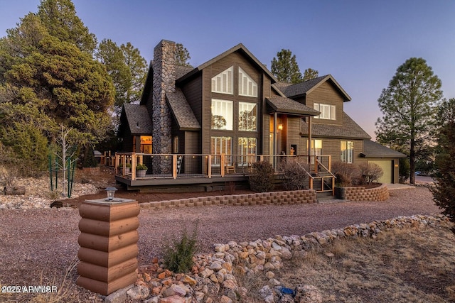 view of front of property featuring an attached garage, roof with shingles, and a chimney