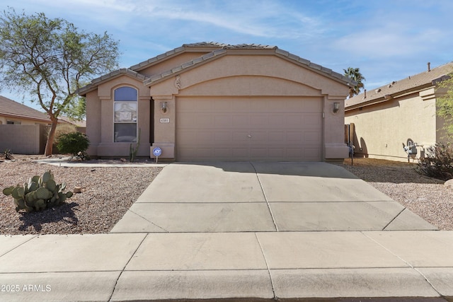 ranch-style home with driveway, an attached garage, a tile roof, and stucco siding