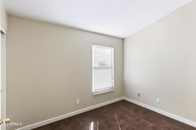 unfurnished room with dark colored carpet and baseboards