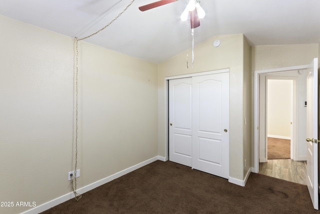 unfurnished bedroom with lofted ceiling, a closet, carpet flooring, ceiling fan, and baseboards