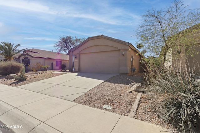 view of front of property featuring a garage, driveway, a tiled roof, and stucco siding