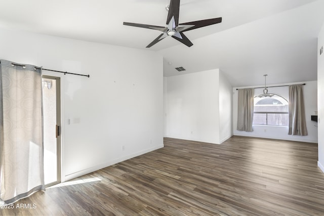 spare room featuring visible vents, a barn door, ceiling fan, wood finished floors, and baseboards