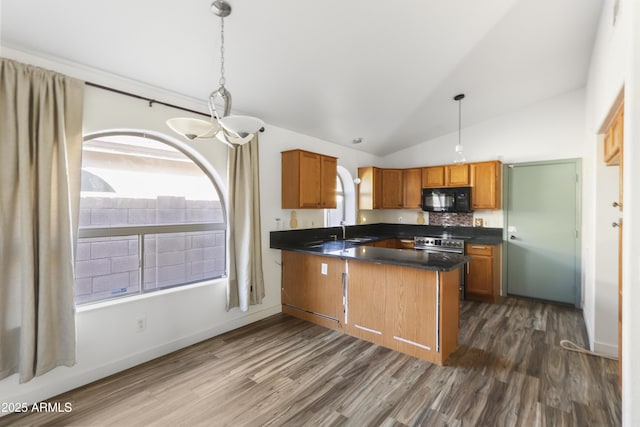 kitchen with black microwave, a peninsula, dark countertops, and a healthy amount of sunlight