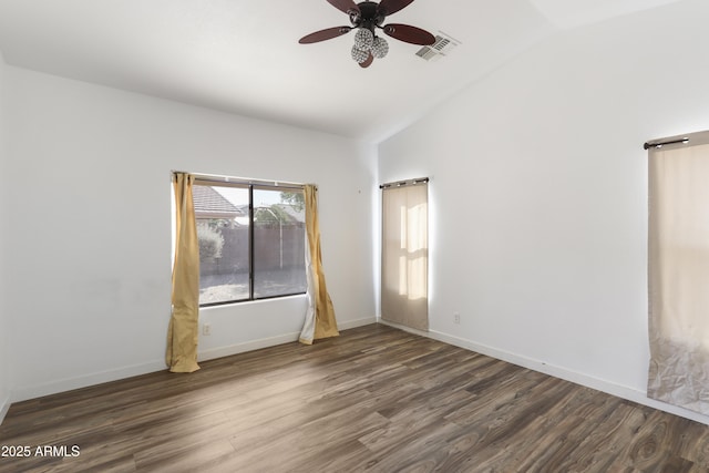 empty room featuring lofted ceiling, baseboards, visible vents, and wood finished floors