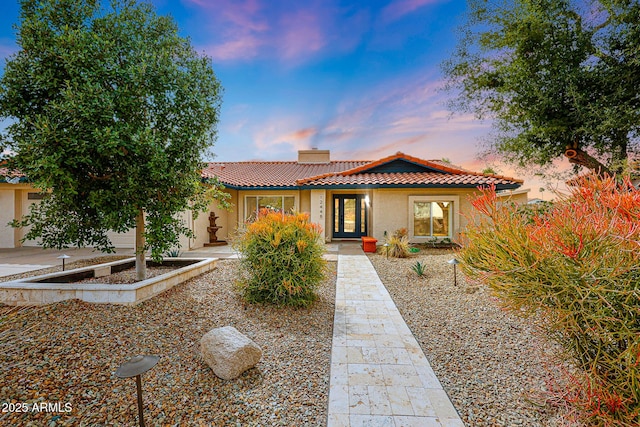 view of front of house with a tile roof, a chimney, and stucco siding