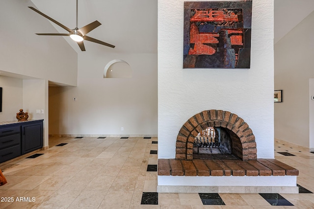 living area with a towering ceiling, ceiling fan, visible vents, and a fireplace with raised hearth