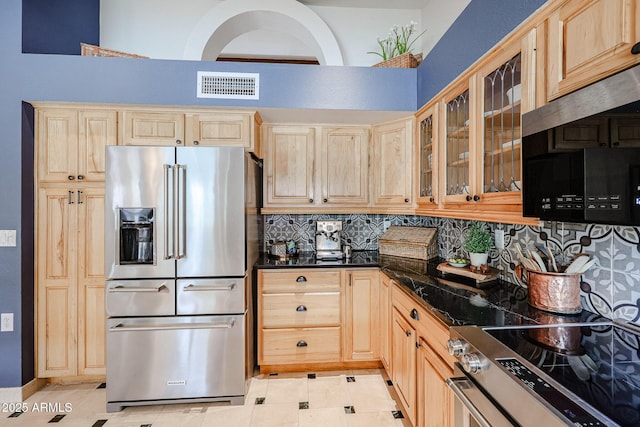 kitchen featuring appliances with stainless steel finishes, dark countertops, visible vents, and light brown cabinets