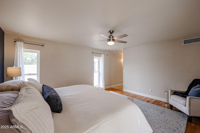 bedroom featuring light wood-style floors, visible vents, ceiling fan, and baseboards