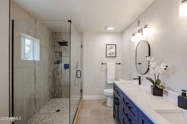 bathroom featuring double vanity, toilet, a stall shower, a sink, and baseboards