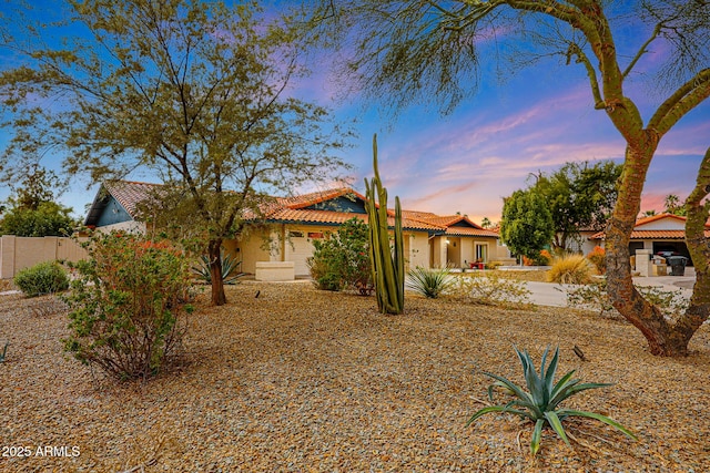 view of front facade with a tile roof, fence, and stucco siding