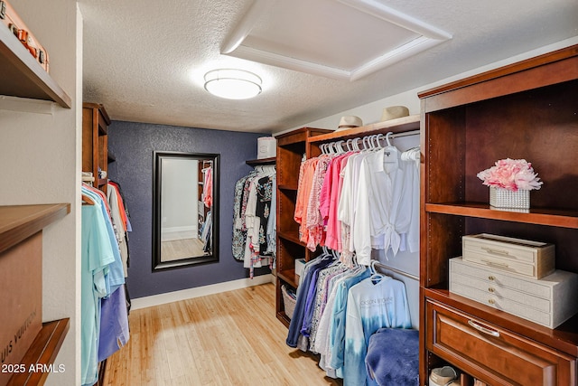 walk in closet featuring attic access and light wood-style floors