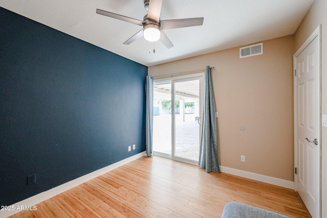 empty room featuring light wood finished floors, baseboards, visible vents, and ceiling fan