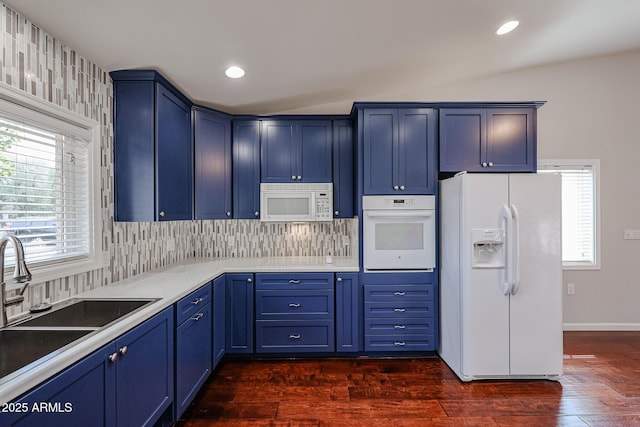 kitchen featuring blue cabinets, white appliances, a healthy amount of sunlight, and a sink