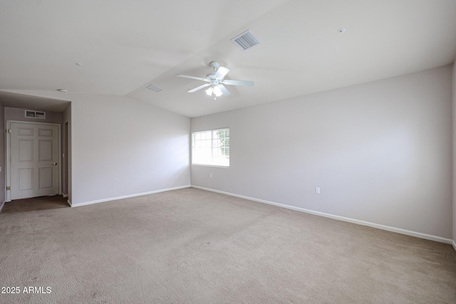 carpeted empty room featuring visible vents, vaulted ceiling, and baseboards