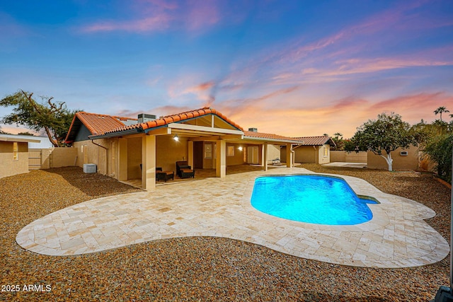 pool at dusk featuring a fenced in pool, a patio area, and a fenced backyard