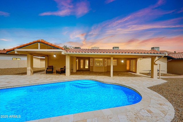 exterior space featuring fence, a tile roof, stucco siding, an outdoor pool, and a patio area