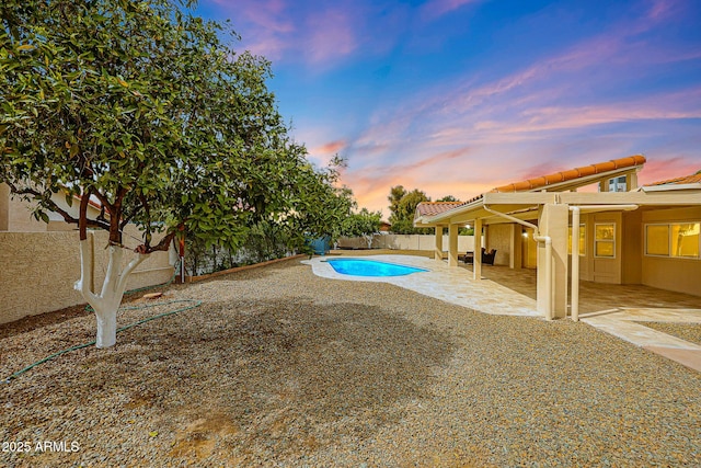 pool at dusk featuring a patio area, a fenced backyard, and a fenced in pool