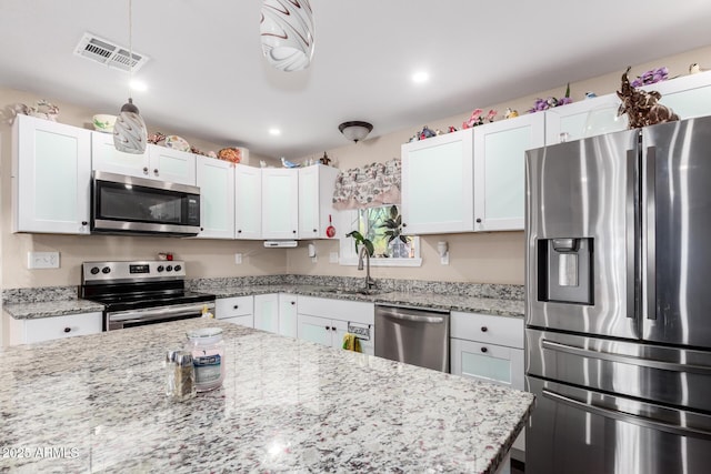 kitchen with stainless steel appliances, visible vents, white cabinetry, and a sink