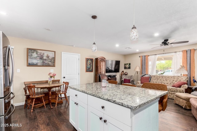 kitchen with stainless steel refrigerator with ice dispenser, open floor plan, dark wood finished floors, and light stone countertops