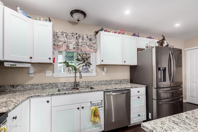 kitchen with dark wood-style flooring, appliances with stainless steel finishes, a sink, light stone counters, and white cabinetry