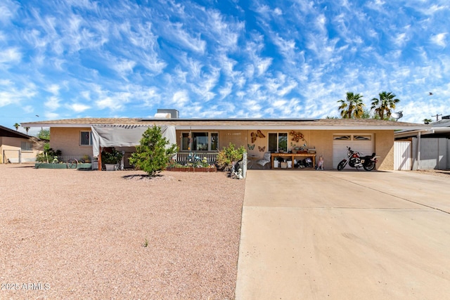 single story home featuring a porch, a garage, driveway, and solar panels