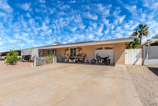 view of front of house with fence, a garage, stucco siding, roof mounted solar panels, and concrete driveway