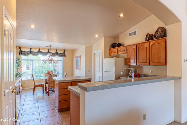15371 W Piccadilly Rd, Goodyear, AZ 85395 - kitchen with a peninsula, freestanding refrigerator, tile counters, visible vents, and recessed lighting
