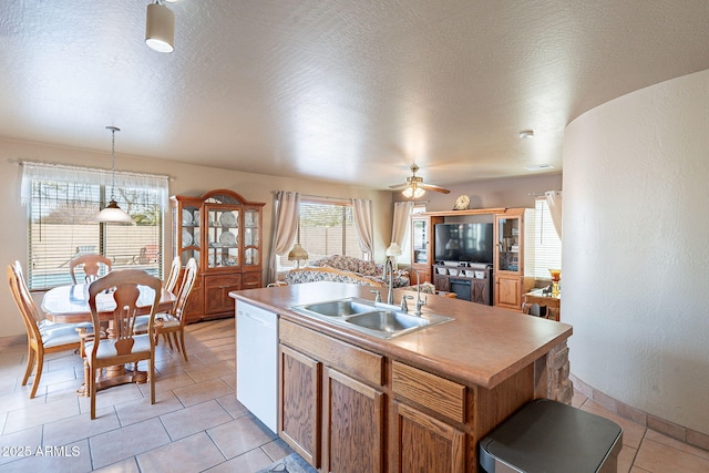 kitchen featuring pendant lighting, dishwasher, sink, a kitchen island with sink, and a textured ceiling