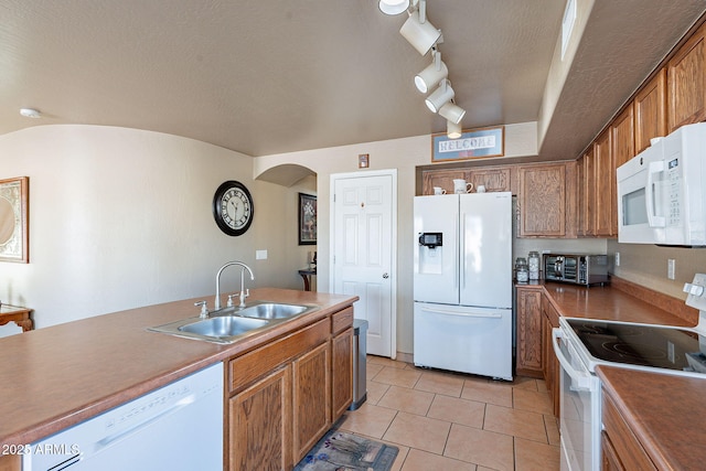 kitchen with sink, white appliances, track lighting, a textured ceiling, and light tile patterned flooring