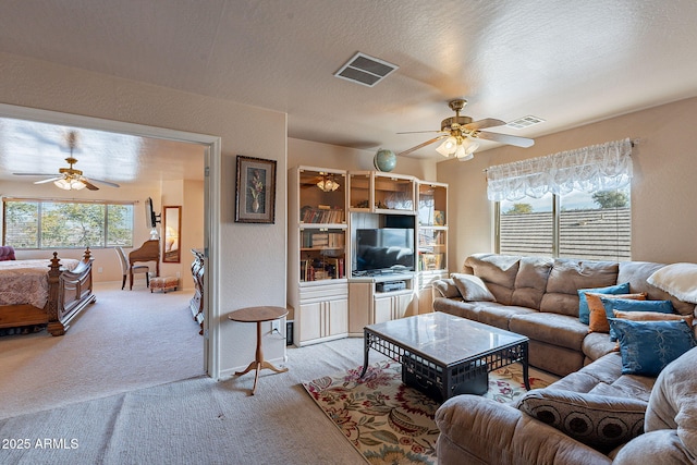 carpeted living room featuring ceiling fan and a textured ceiling