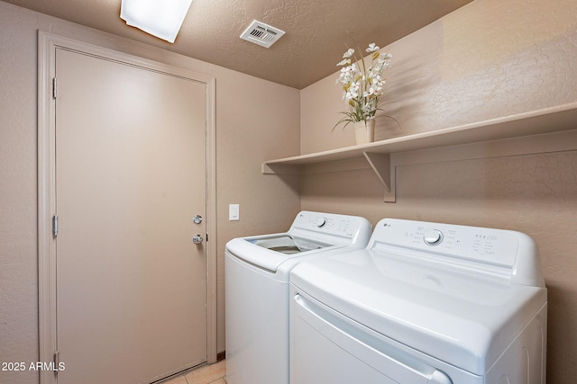 clothes washing area with light tile patterned floors, independent washer and dryer, and a textured ceiling