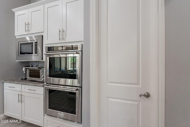 9345 W Robin Ln, Peoria, AZ 85383 - kitchen featuring stainless steel appliances, white cabinetry, light stone counters, and baseboards