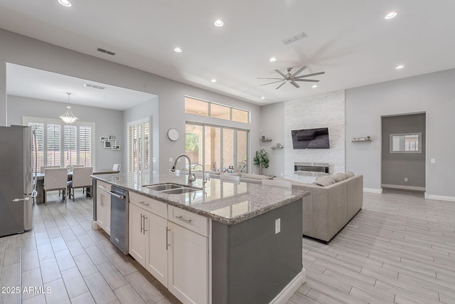 9345 W Robin Ln, Peoria, AZ 85383 - kitchen featuring stainless steel appliances, a sink, a fireplace, a center island with sink, and white cabinets