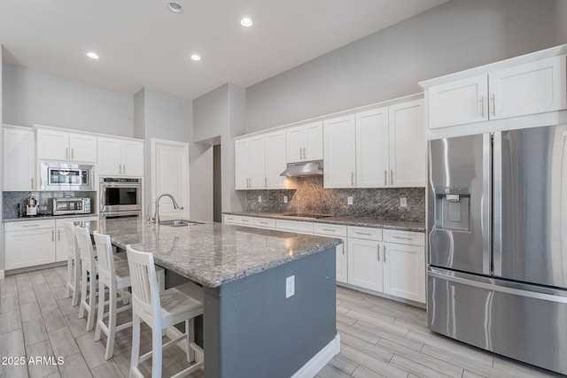 9345 W Robin Ln, Peoria, AZ 85383 - kitchen featuring stainless steel appliances, a sink, under cabinet range hood, wood tiled floors, and white cabinetry