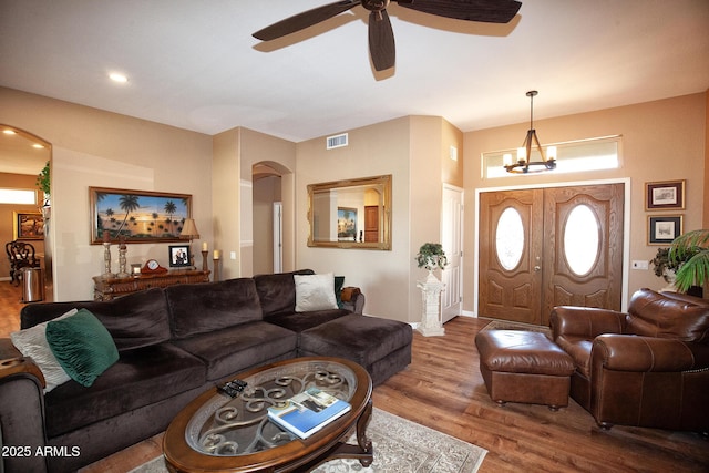 living room featuring ceiling fan with notable chandelier and hardwood / wood-style floors