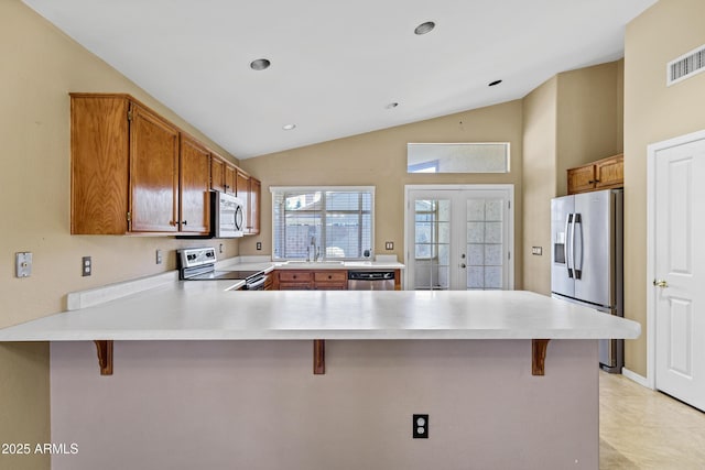 625 W Douglas Ave, Gilbert, AZ 85233 - kitchen featuring stainless steel appliances, a peninsula, vaulted ceiling, light countertops, and a kitchen bar