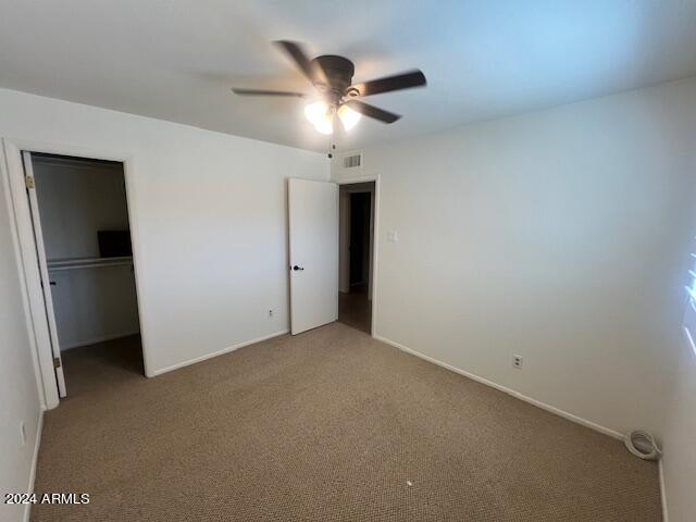 unfurnished bedroom with a walk in closet, a closet, and ceiling fan