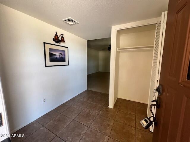 unfurnished bedroom featuring a textured ceiling, dark tile patterned flooring, and a closet