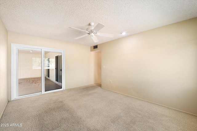 carpeted spare room with ceiling fan, a textured ceiling, and visible vents