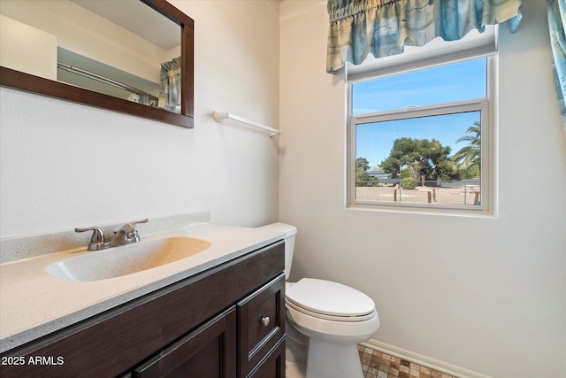 bathroom featuring toilet, baseboards, and vanity