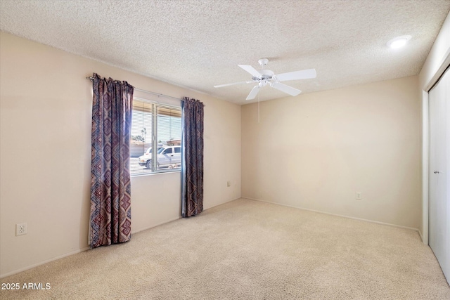 carpeted empty room featuring a textured ceiling and a ceiling fan