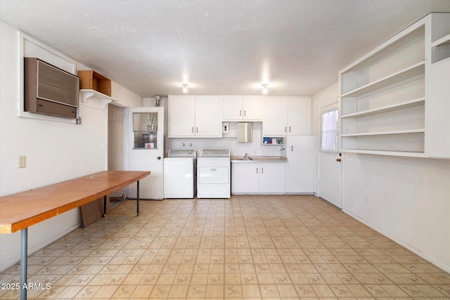 kitchen with washer and clothes dryer, light floors, open shelves, white cabinets, and a sink