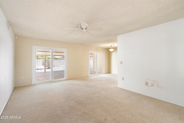 empty room with light carpet, ceiling fan, and a textured ceiling