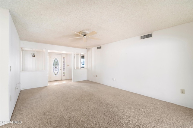 spare room with light carpet, visible vents, and a textured ceiling